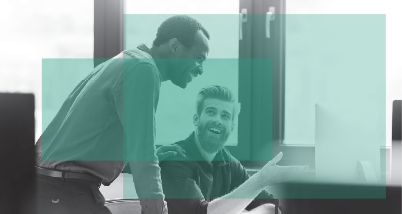 Photo of a man working and smiling while pointing to a computer